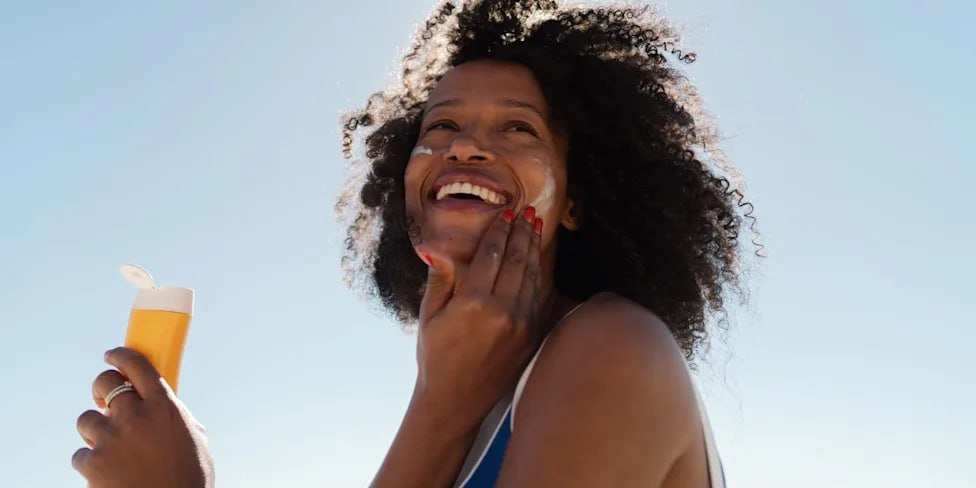 Woman applying sunscreen outdoors — sun protection in action